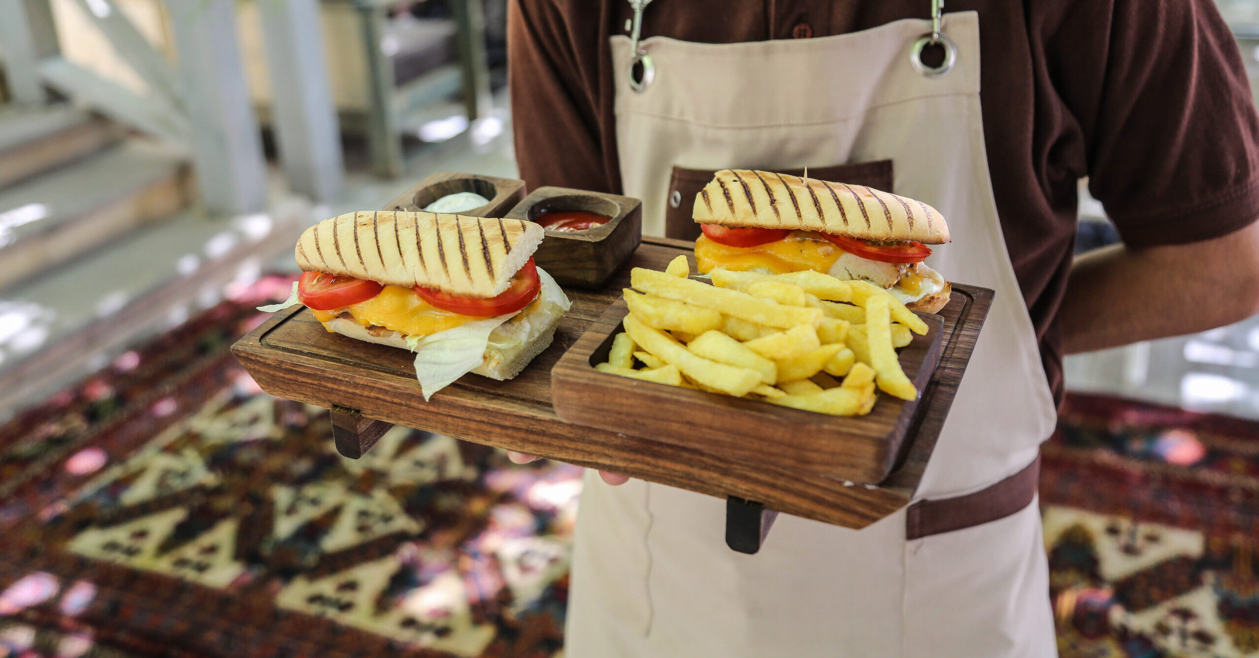 Server carrying two sandwiches on a tray